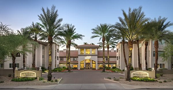 A residential building with palm trees lining the entrance.