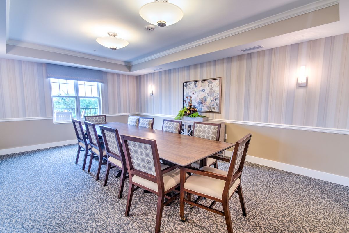 A well-lit conference room with a large table and chairs, featuring modern decor and carpeting.