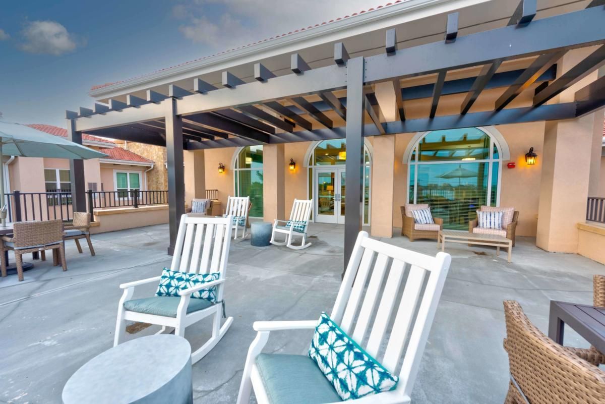 A cozy outdoor patio featuring rocking chairs and a pergola.