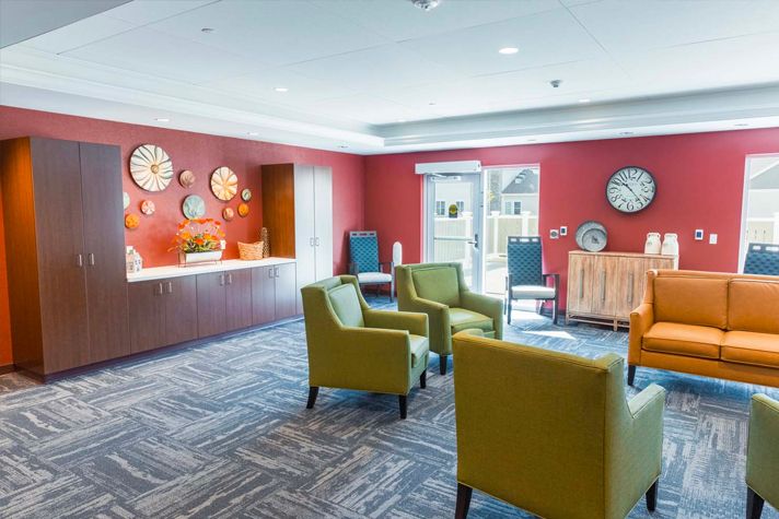 A cozy lounge area with stylish chairs and a collection of decorative clocks on a red accent wall.