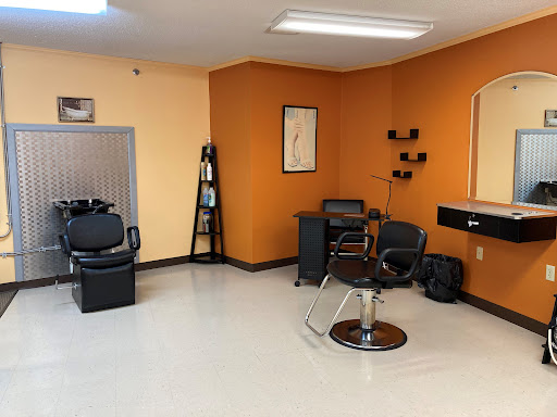 A modern and minimalistic hair salon setup featuring sleek furniture and vibrant orange walls.