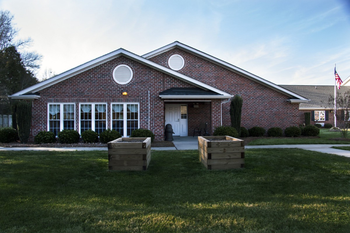 A brick building with a manicured lawn and two wooden planters at the entrance.