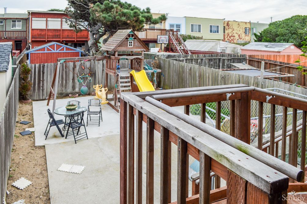 A backyard with a playground slide and outdoor seating area in an urban setting.