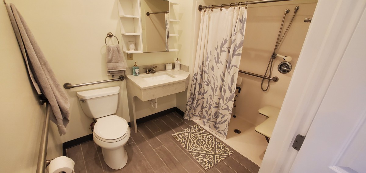 A modern bathroom with a sink, toilet, and shower equipped with a patterned curtain.