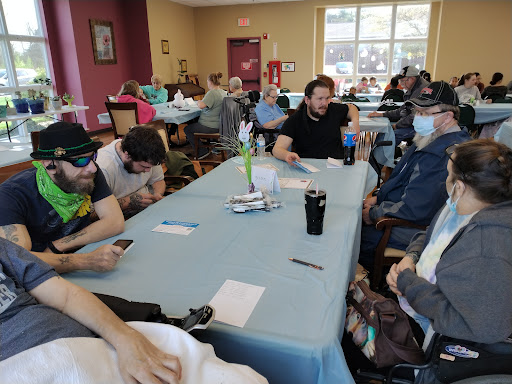 A group of people engaged in conversation around a table in a community space.