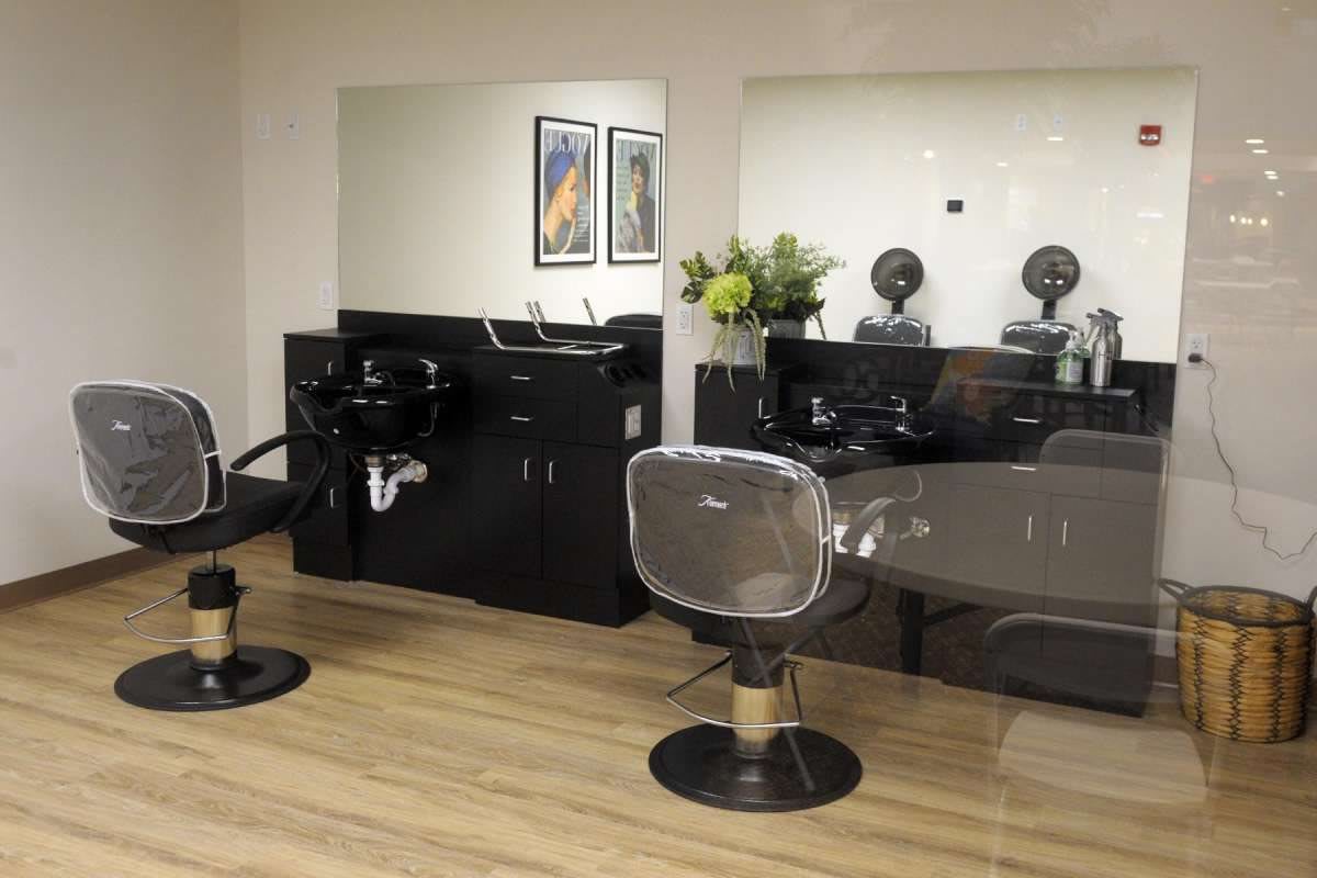 A modern hair salon interior with styling chairs, mirrors, and washing stations.