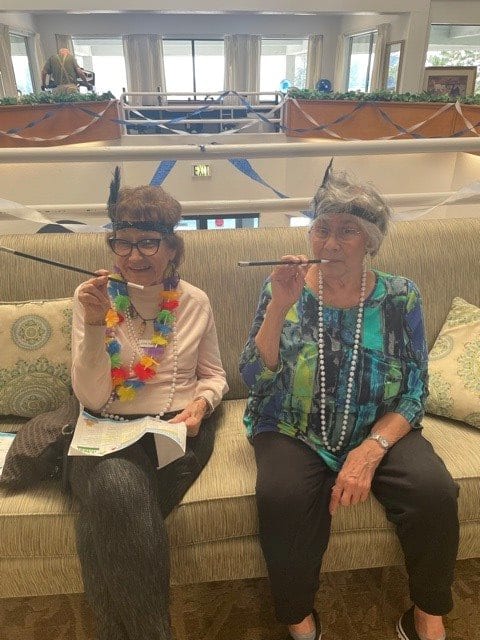 Two seniors wearing unicorn horns and holding funny glasses, enjoying a lighthearted moment together.