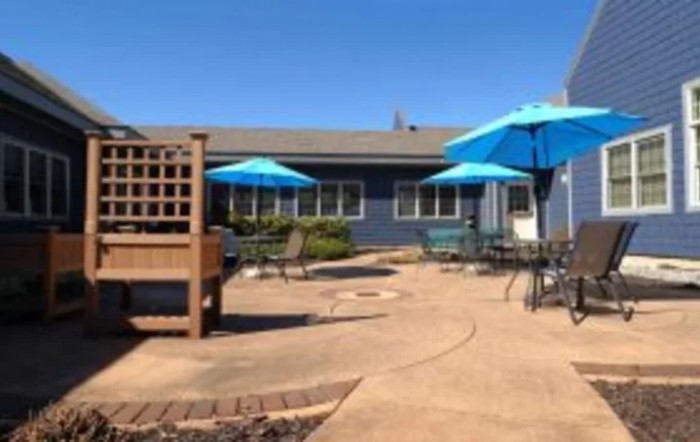 A sunny patio area with blue umbrellas and outdoor furniture.