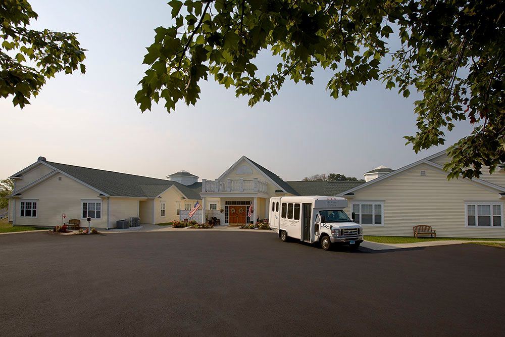 A residential building with a van parked in the driveway surrounded by trees.