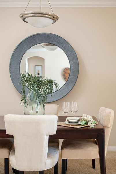 A stylish dining room with a large round mirror and elegant table setting.