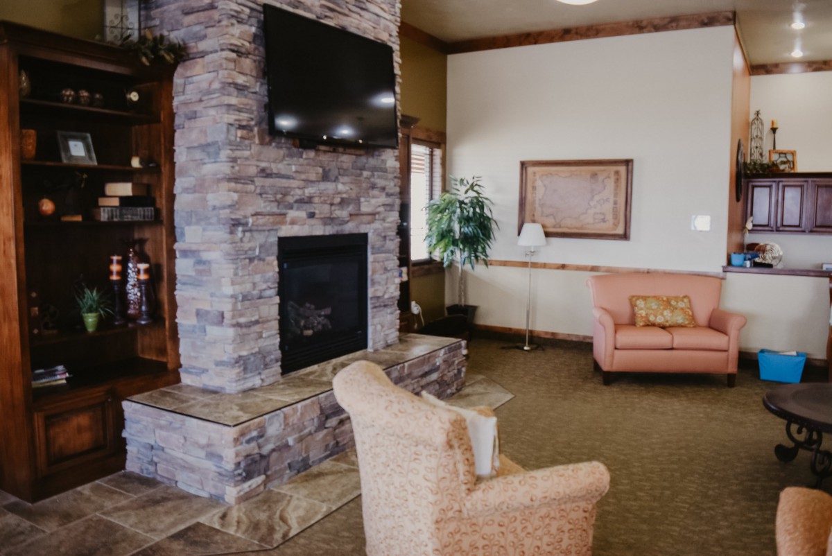 A cozy living room with a stone fireplace and a mounted TV, complemented by comfortable seating and decor.