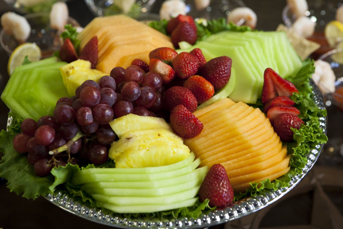 A colorful fruit platter featuring grapes, strawberries, pineapple, and sliced melon.