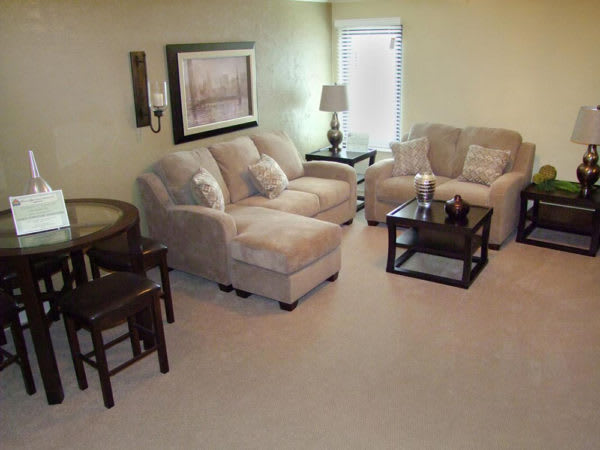 A cozy living room with a sofa, armchair, and coffee table, complemented by a lamp and wall artwork.
