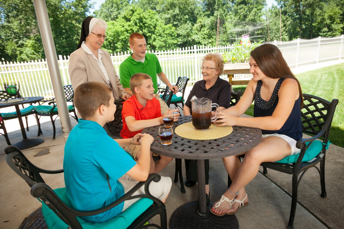 A family enjoying drinks and conversation on a sunny outdoor patio.