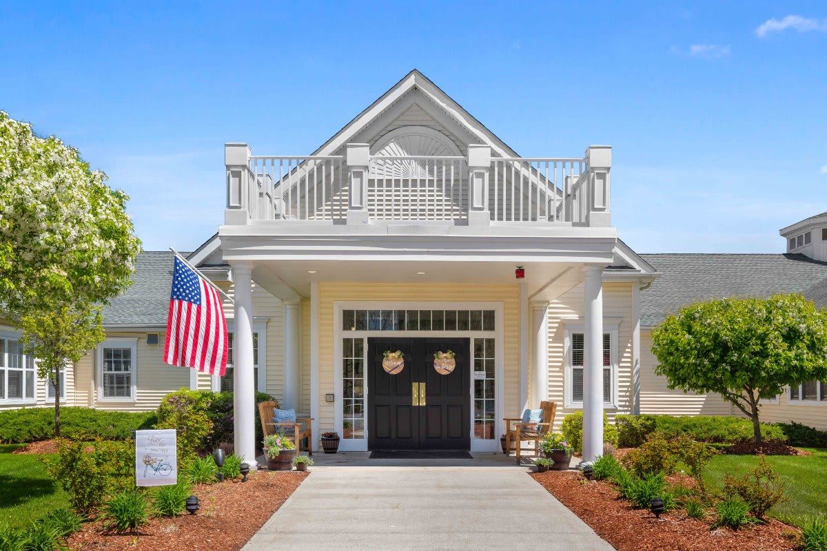 A beautifully designed building entrance with an American flag and well-maintained landscaping.