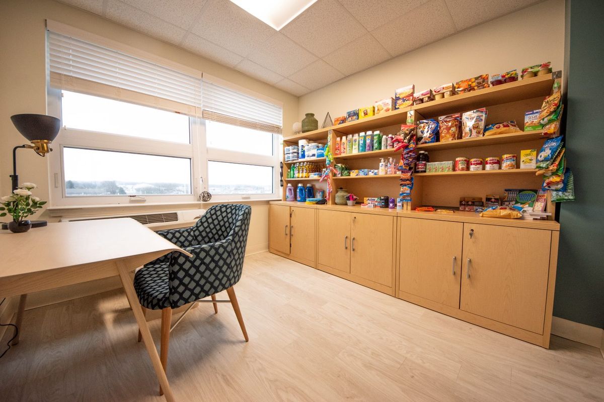 A well-organized office space with a desk, comfortable chair, and shelves full of colorful items.
