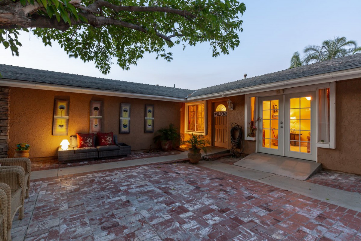 A cozy courtyard with brick flooring and warm lighting in the evening.