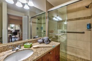 A modern bathroom featuring a granite countertop, glass shower doors, and neatly arranged towels.
