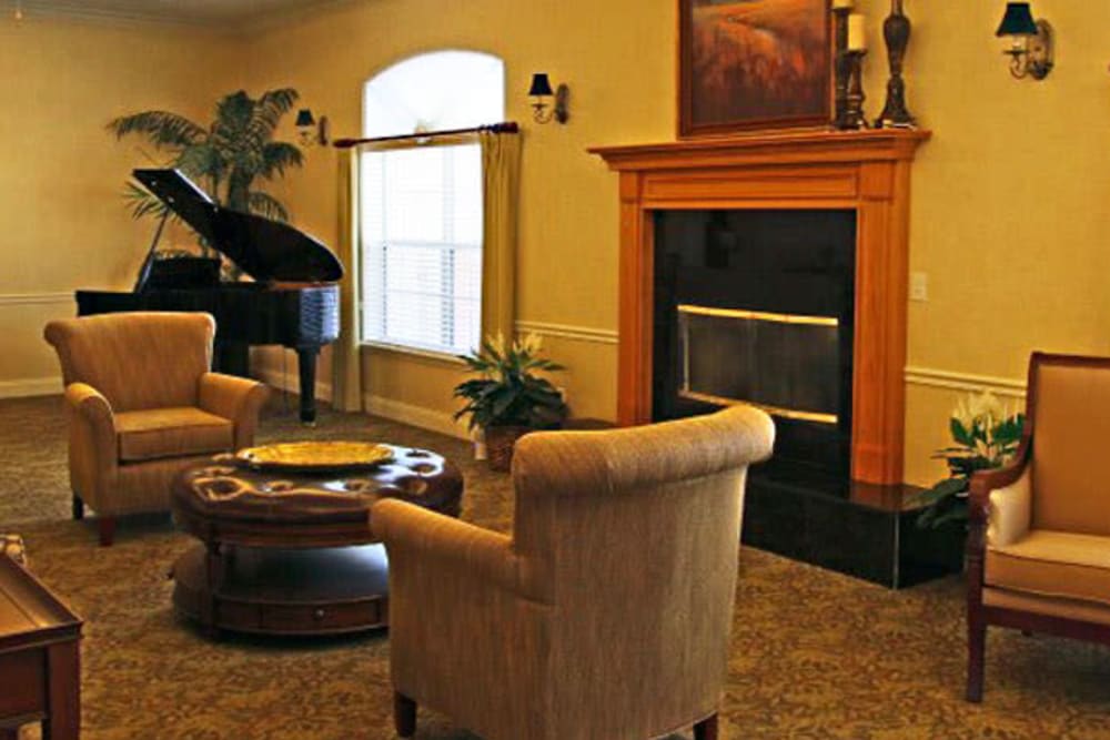 A cozy living room featuring a grand piano, comfortable seating, and a fireplace.