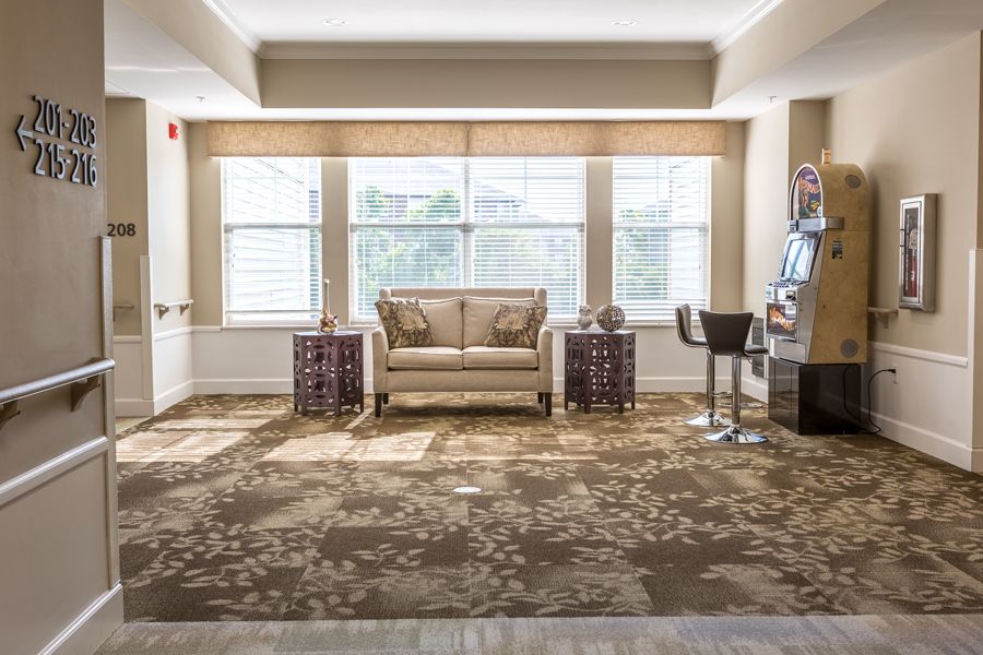 A well-lit living room with a sofa and chairs, featuring large windows and decorative carpet.