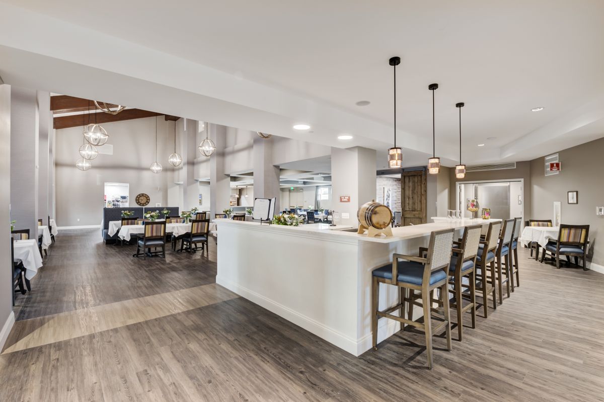A modern kitchen with a spacious open layout, featuring a central island with barstools and elegant pendant lighting.
