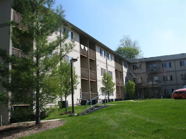 A view of a residential apartment building surrounded by greenery and trees.