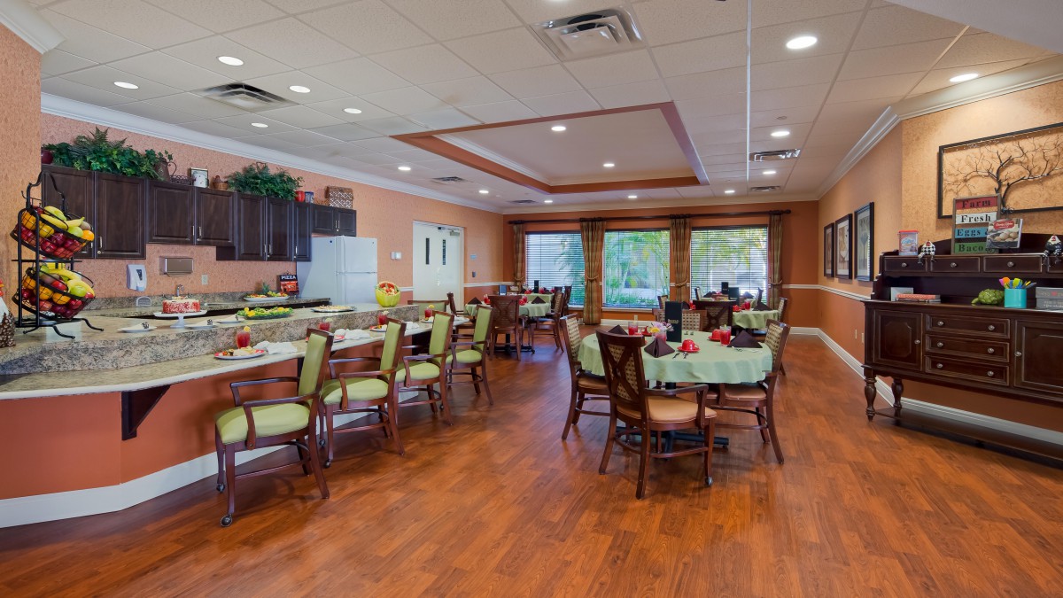 A well-decorated dining area with multiple tables and chairs, featuring large windows and wood flooring.