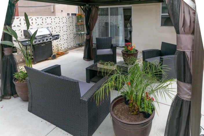 A cozy patio setup with wicker furniture and potted plants.