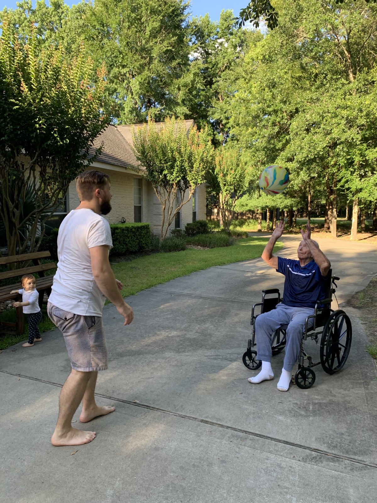 A family enjoying a moment together outdoors, with a person in a wheelchair interacting with others on a sunny day.