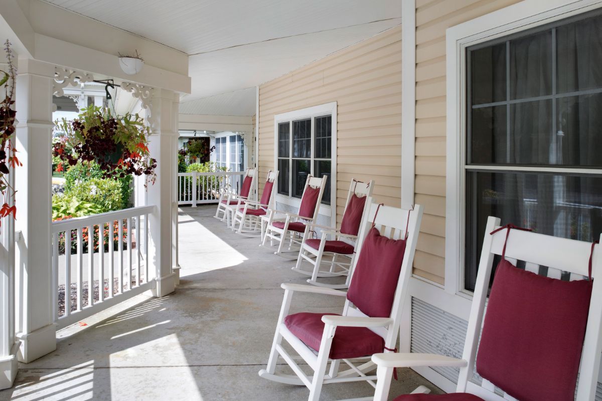 A serene porch featuring red rocking chairs and hanging flower baskets.