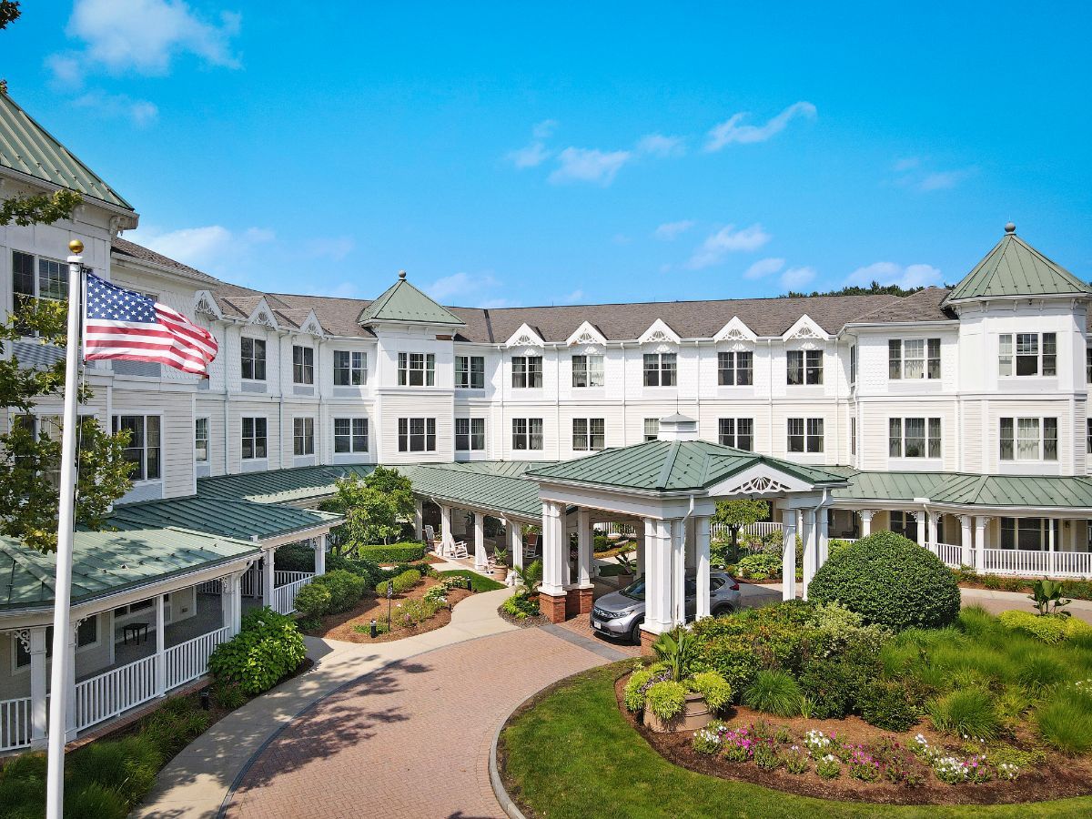 A grand hotel entrance with lush landscaping and an American flag flying above.
