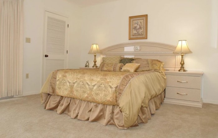 A cozy bedroom with a neatly made bed, elegant decor, and soft lighting.