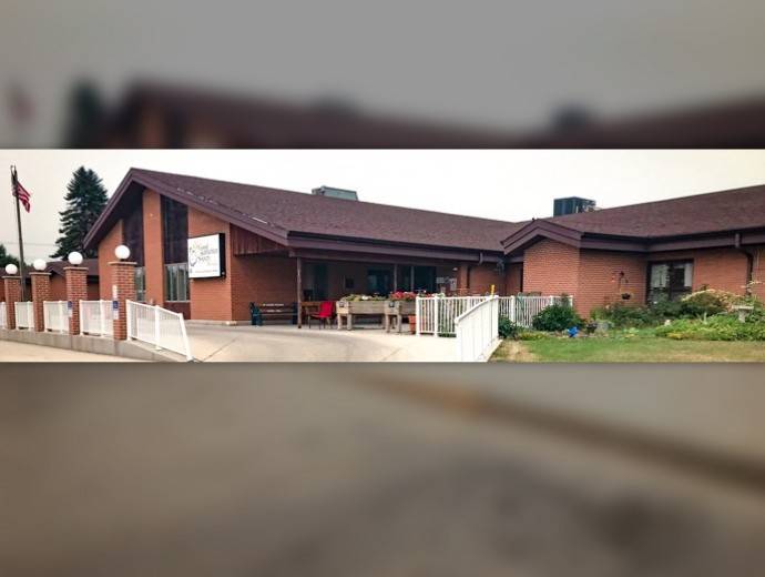 A brick house with a pitched roof and fenced yard.