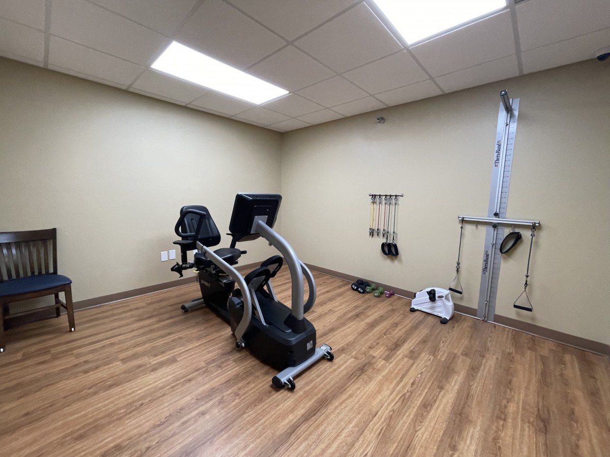 A minimalist exercise room featuring a stationary bike on a wooden floor.