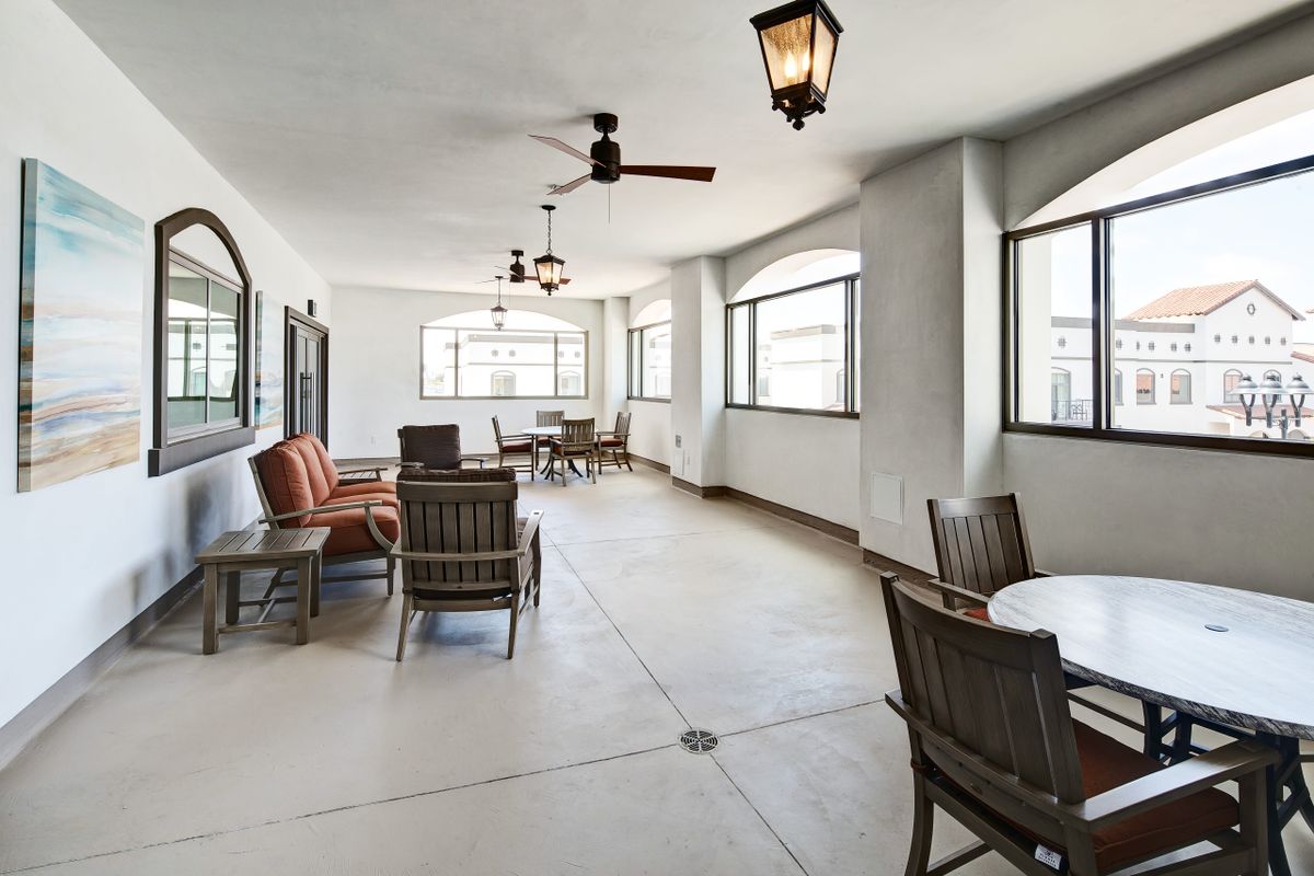 A bright indoor seating area with chairs and tables, featuring large windows and stylish light fixtures.