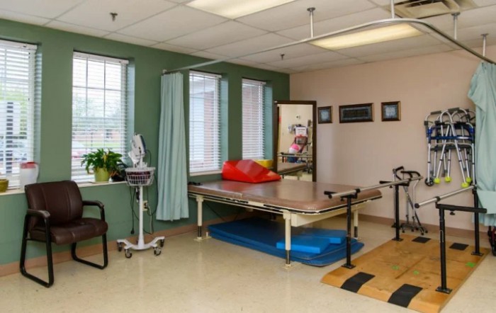 A physical therapy room equipped with a treatment table and various exercise equipment.