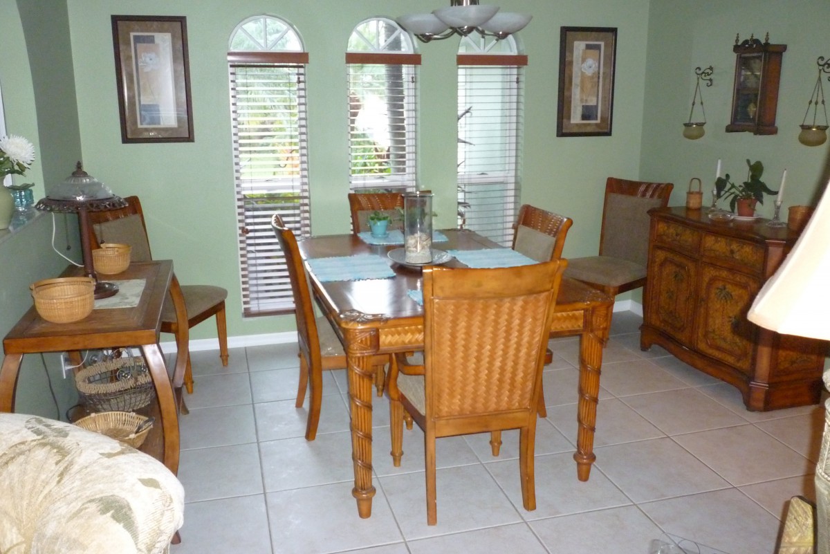 A cozy dining room with a wooden table and chairs, decorated with art pieces and natural light from the windows.