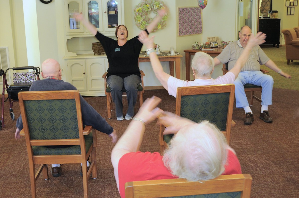A group of seniors participating in a lively chair exercise session indoors.
