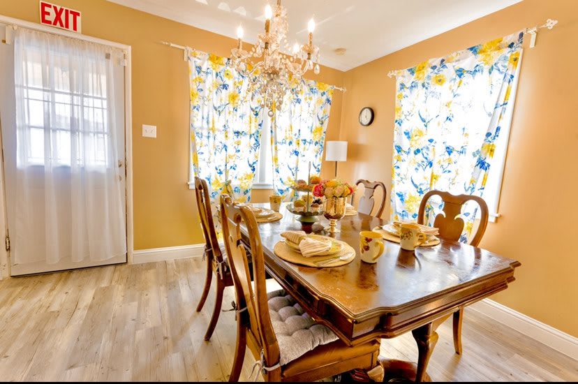 A warm and inviting dining room with a wooden table set for a meal, adorned with a chandelier overhead.
