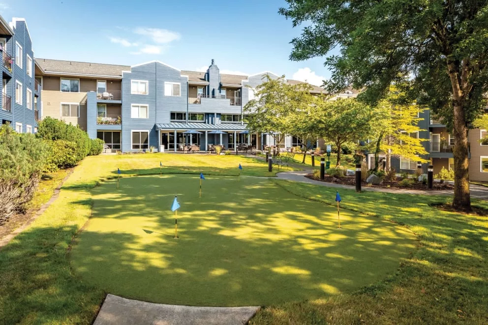 A sunny view of a building with a well-maintained lawn and trees.
