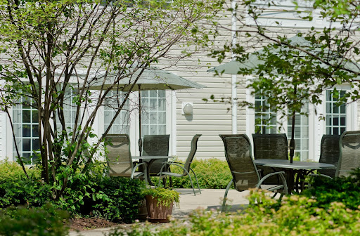A serene outdoor patio area with chairs and tables surrounded by greenery.