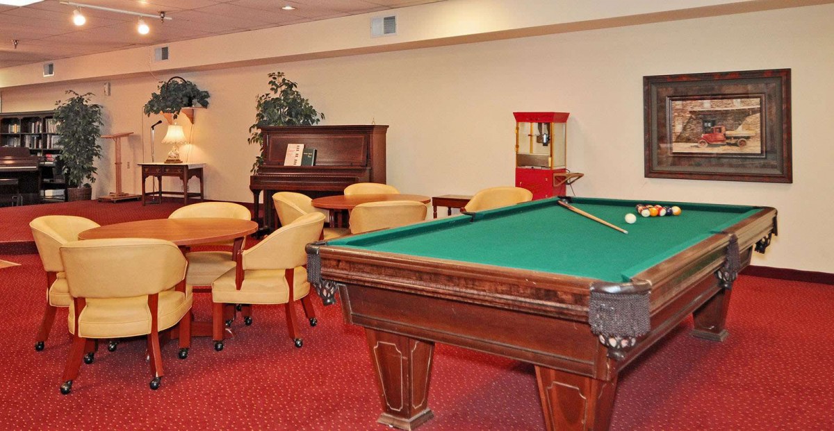 A cozy recreation room featuring a pool table, piano, and seating area with a popcorn machine.