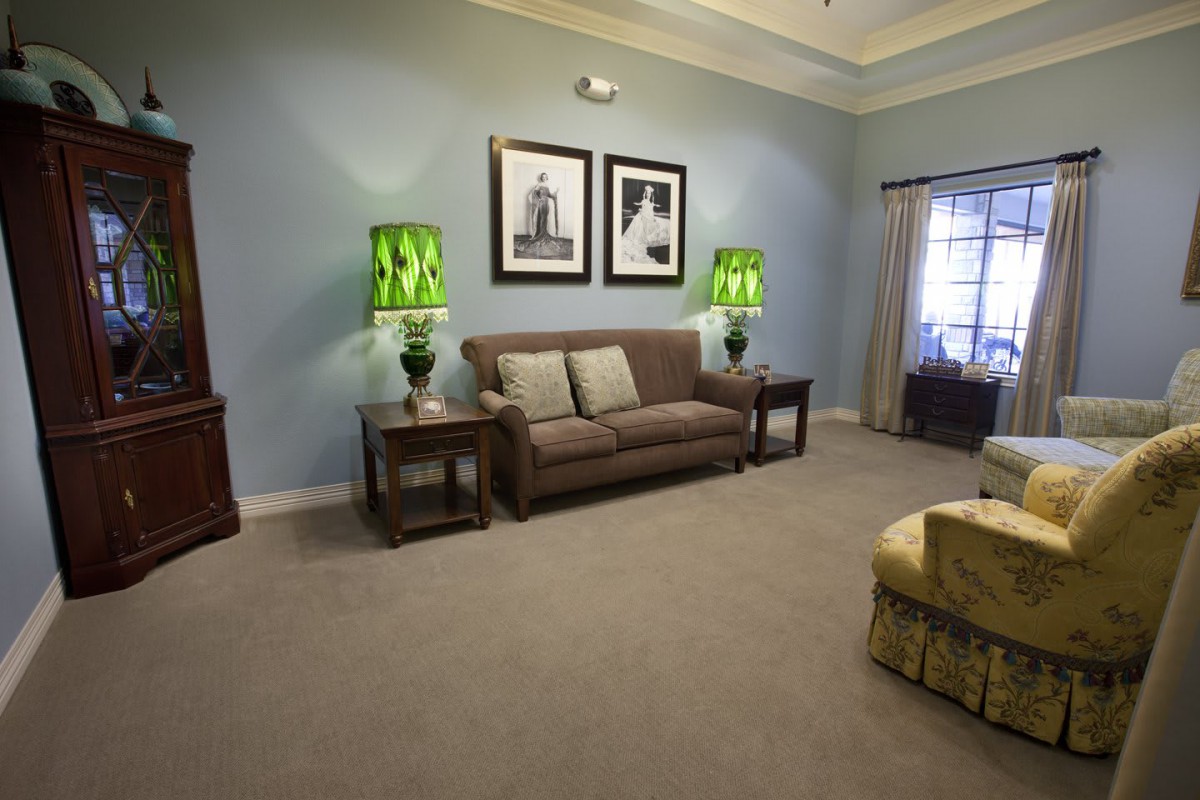A cozy living room featuring a sofa, vibrant green lamps, and framed artwork.