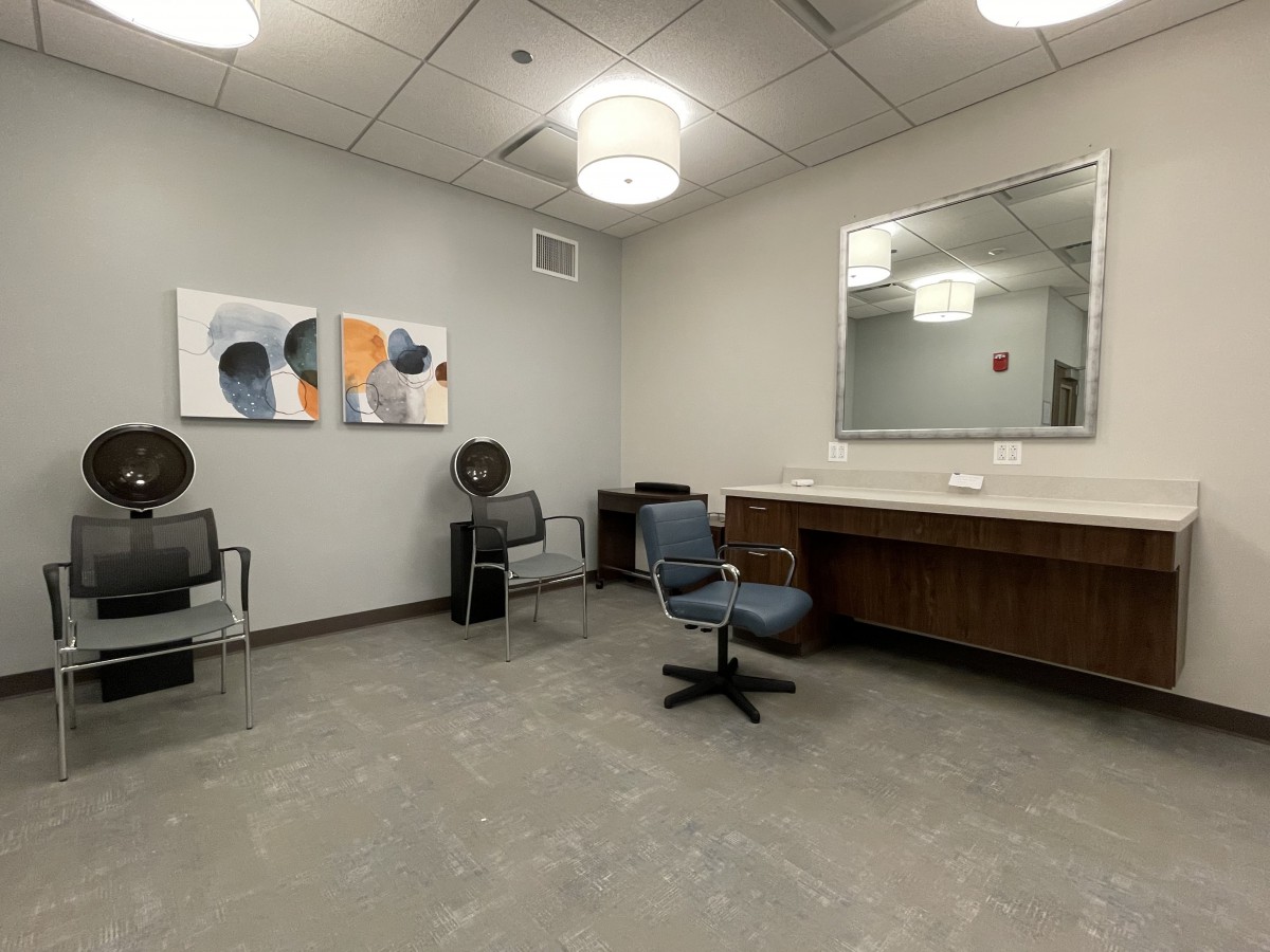 A modern salon interior with chairs, a mirror, and hair dryers.