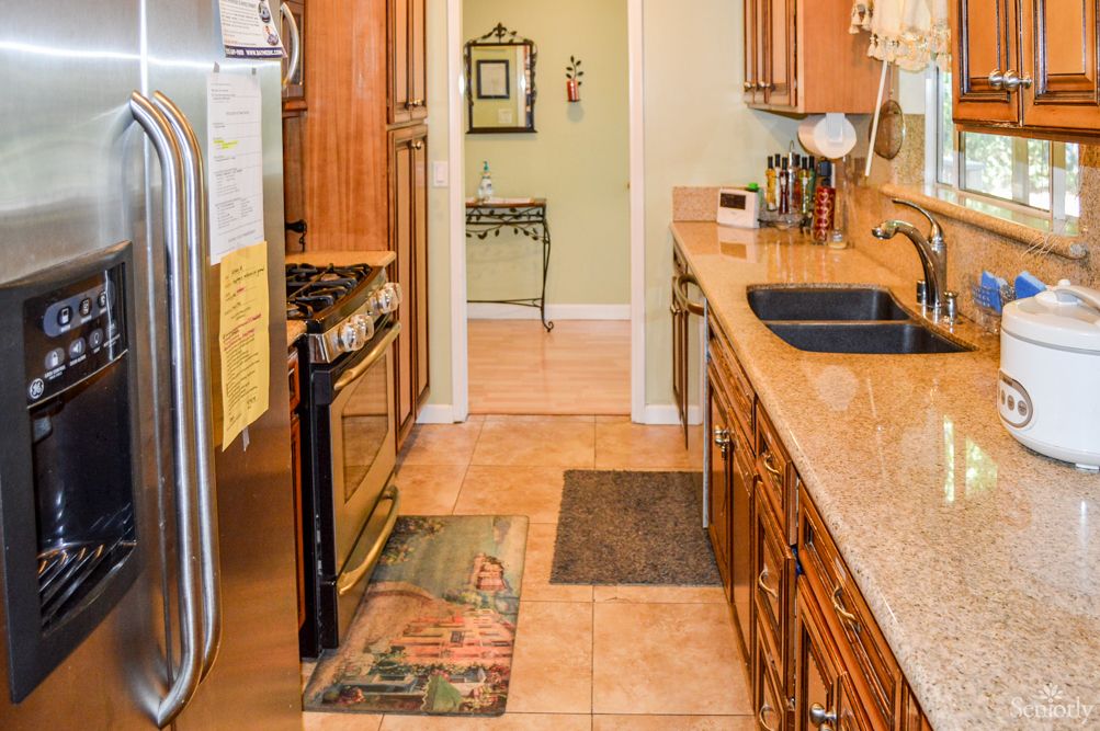 A modern kitchen featuring wooden cabinets, a tile floor, and stainless steel appliances.