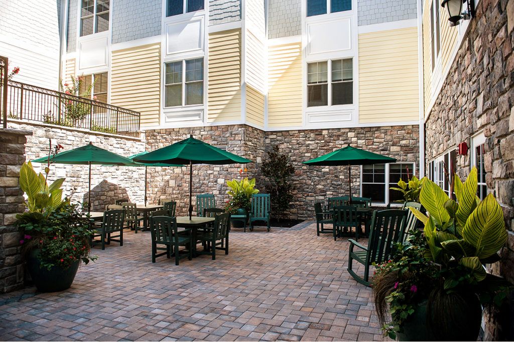 An outdoor patio with tables, chairs, and umbrellas next to a building.