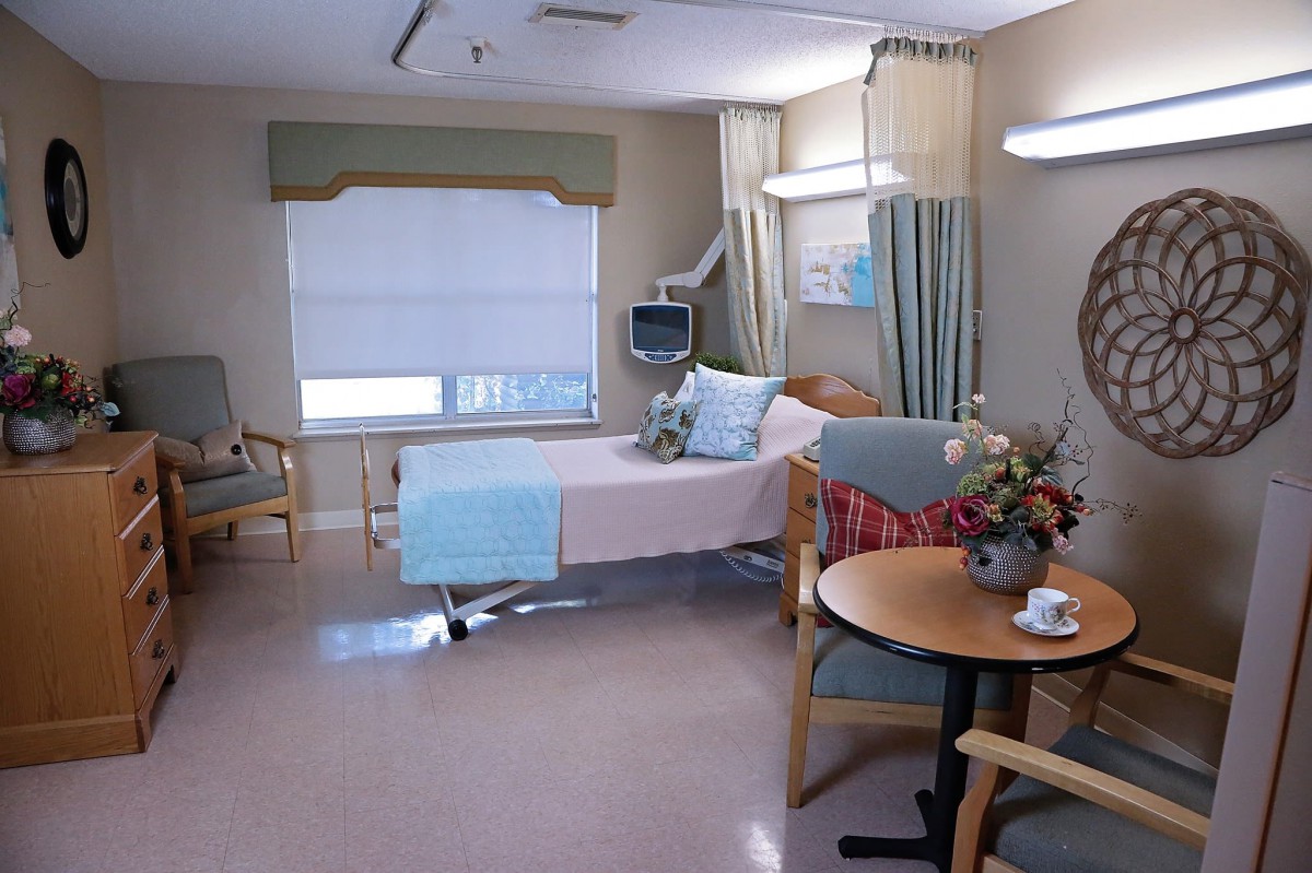 A hospital room featuring a bed, medical equipment, and seating area.