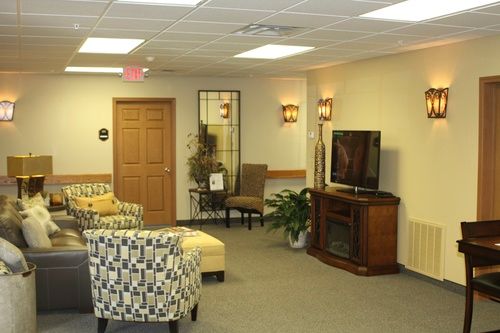A cozy waiting room with comfortable seating, a television, and indoor plants.
