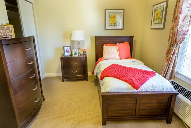 A cozy bedroom with a single wooden bed, matching nightstand, and bright decor.