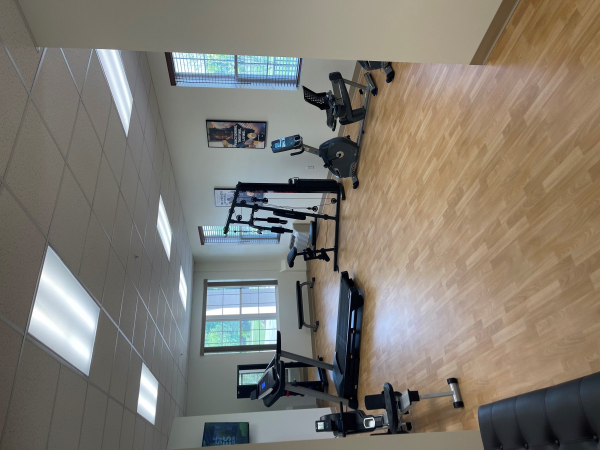 A well-lit gym with various exercise machines and equipment.